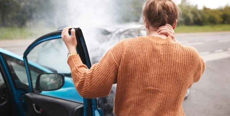 Photo of woman holding neck after car accident.